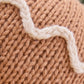 Close-up of the Baby Gingerbread - Icing White by Cuddle + Kind, showcasing brown cotton yarn handcrafted into a knitted fabric with a wavy white yarn pattern stitched on its surface.
