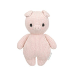 The Piglet - Baby 7" by Cuddle + Kind is a pink, hand-knit stuffed pig made from heirloom-quality Peruvian cotton yarn, featuring black eyes and a small snout. It stands upright against a white background.