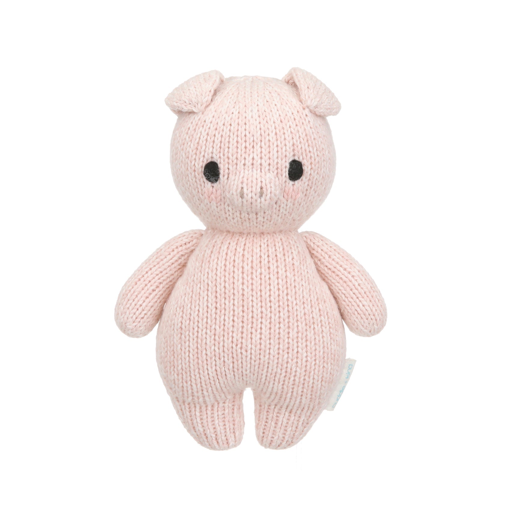 The Piglet - Baby 7" by Cuddle + Kind is a pink, hand-knit stuffed pig made from heirloom-quality Peruvian cotton yarn, featuring black eyes and a small snout. It stands upright against a white background.