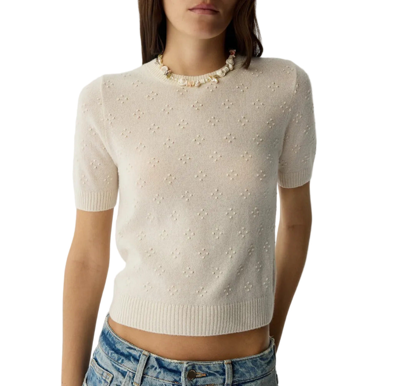 A woman wearing the Compass Sweater Tee by Guest in Residence, a lightweight cashmere short-sleeve top with a subtle floral pattern, styled with blue jeans and a beaded necklace.