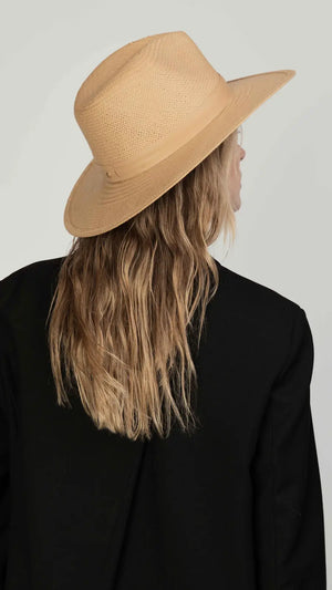 Person with long, wavy blonde hair wears the Janessa Leone Simone Hat and a black jacket, shown from behind against a plain background for a timeless look.