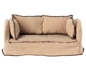 The Maileg Couch, Miniature is a small beige sofa made from linen-quality fabric with dark edge stitching and two matching cushions, ideal for your dollhouse.