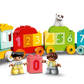 The LEGO® DUPLO® Number Train - Learn To Count by LEGO® features blocks numbered 0-9, two child figures, and a white cat on a green block—an ideal educational toy for toddlers to learn numbers while playing.