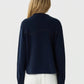A person with long, wavy blonde hair wears the Guest in Residence Cropped Western Shirt in dark navy, styled with off-white jeans, standing facing away from the camera against a plain light background.