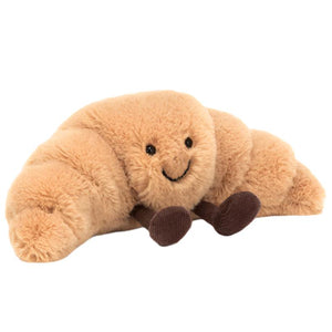 Jellycat's small Amuseables Croissant plush toy features a cheerful face and tiny brown feet, designed in the shape of a croissant.