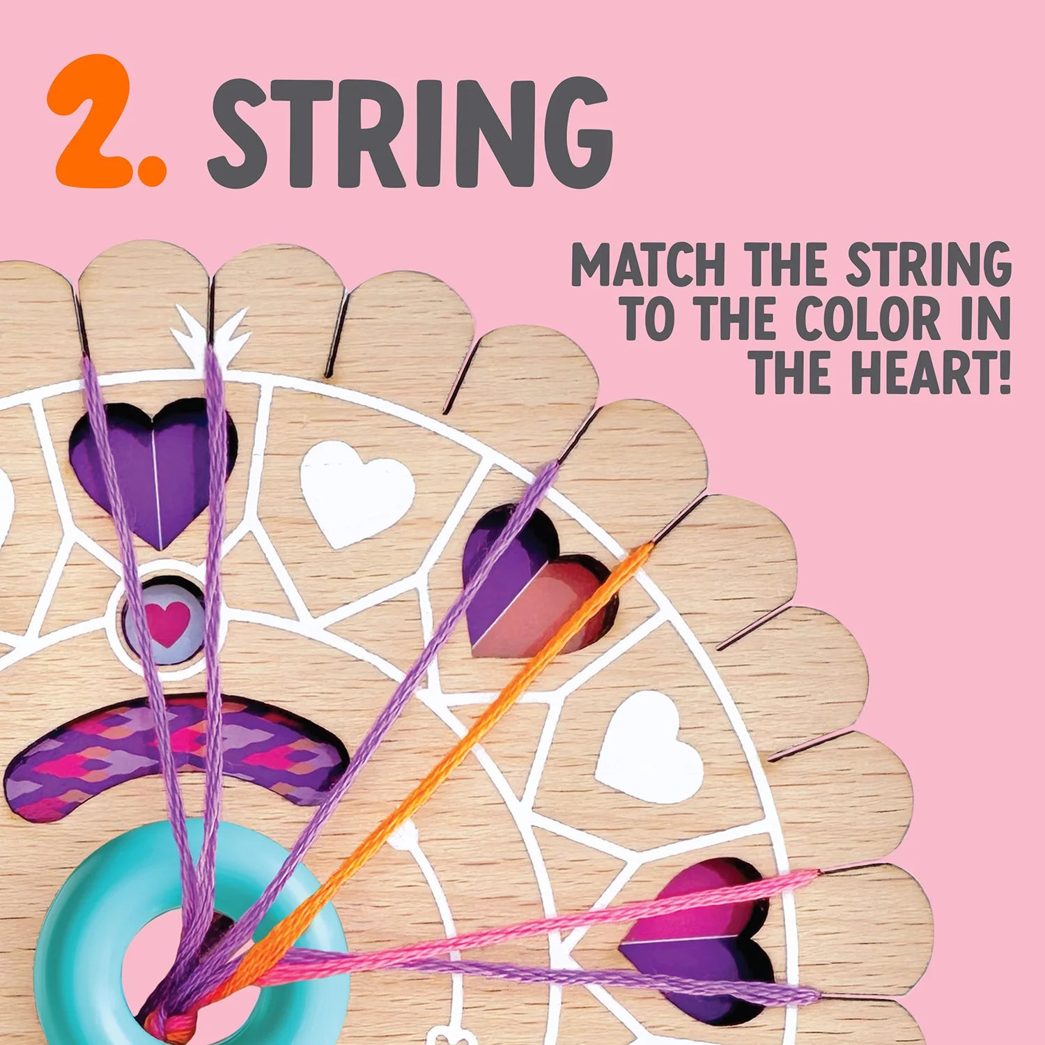 The Bright Stripes Dial-A-Design Bracelet Wheel is a wooden board with colorful strings threaded through heart-shaped holes. It features the text "2. STRING. MATCH THE STRING TO THE COLOR IN THE HEART!" against a pink background, resembling a friendship bracelet maker's toolkit.