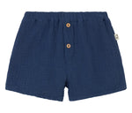 The Cozmo Baby Boys' Dale Shorts feature navy blue textured gauze, an elastic waistband, two wooden front buttons, and a side fabric tag—stylish and comfy toddler shorts.