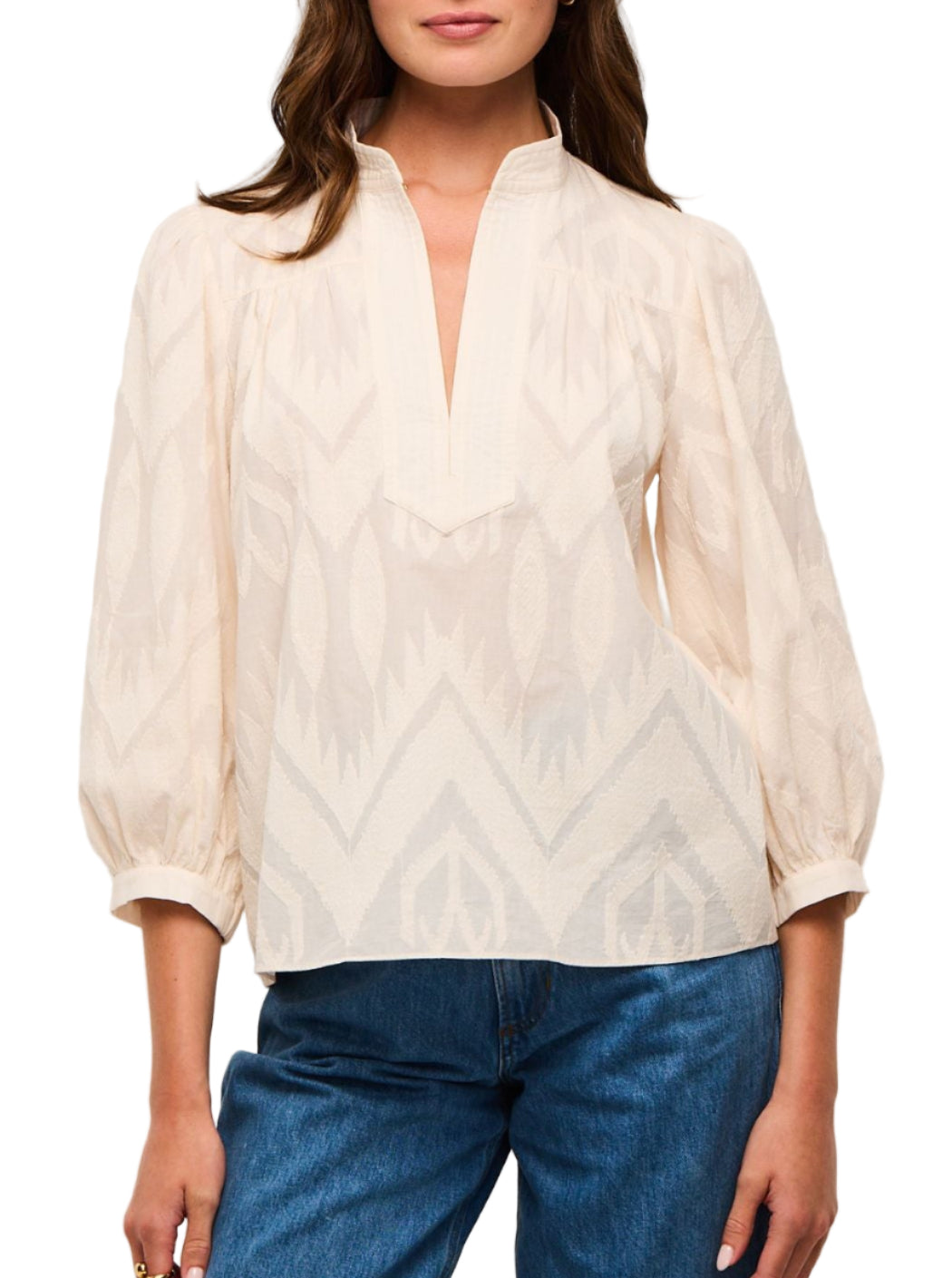 A woman wears the Figue Danilia Top, a lightweight cotton, long-sleeve band collar blouse with a V-notch and relaxed fit, paired with blue jeans.