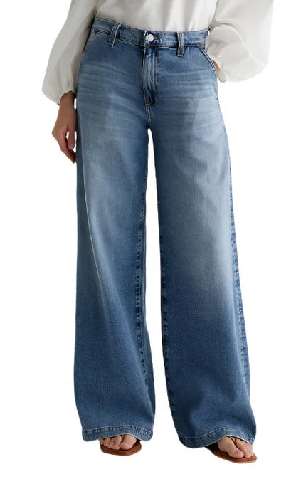 Person wearing AG Stella Jeans by AG Jeans in a high-waisted, light indigo wash with a wide-leg cut, paired with a white long-sleeve blouse, shown from waist to feet.