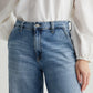 Close-up of a person wearing AG Stella Jeans in light indigo wash and a white blouse with long, puffy sleeves, tucked into the stretch denim jeans from AG Jeans.