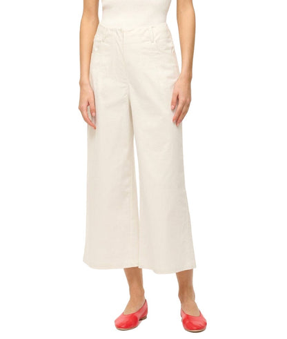 Woman wearing Staud Luca Pant high-waisted wide-leg trousers and red ballet flats, standing against a white background, cropped at the waist.