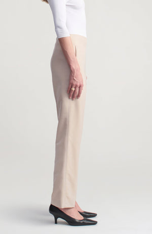 Side view of a person wearing beige wool gazar Nadja Trouser high-waisted trousers cropped at the ankle and black kitten-heel pumps.