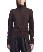 A person wearing the Kallmeyer Leona Silk Wool Cardigan in chocolate brown, featuring a button-up front and funnel collar, paired with black pants and standing against a white background.
