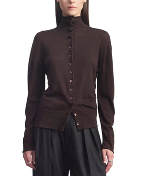A person wearing the Kallmeyer Leona Silk Wool Cardigan in chocolate brown, featuring a button-up front and funnel collar, paired with black pants and standing against a white background.
