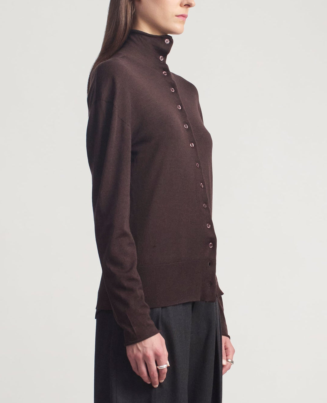 A person wearing the Kallmeyer Leona Silk Wool Cardigan and dark pants, standing sideways against a plain light background.