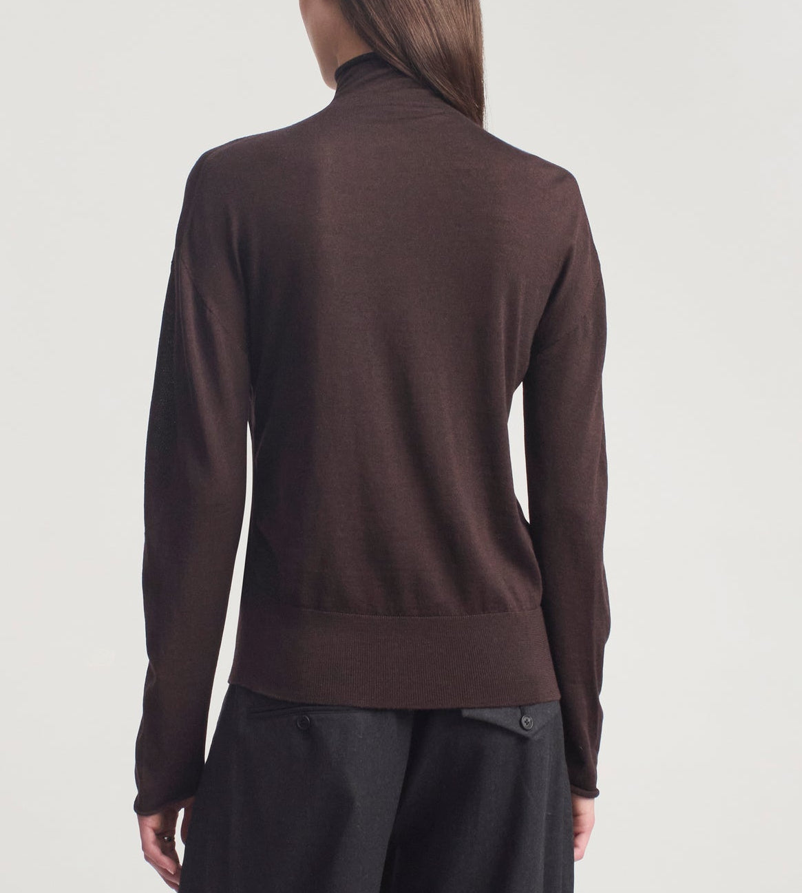 A person wearing the Kallmeyer Leona Silk Wool Cardigan—a long-sleeve, dark brown sweater with a high funnel collar—paired with black pants, shown from the back against a plain light background.