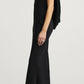 Side profile of a person in a black viscose cady Gilda Bias Dress with a cowl neckline, featuring an attached draped back panel and black heeled sandals.