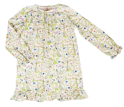 The Girls’ Sunday Morning Dress by Timo & Violet is a long-sleeve, knee-length dress made from soft, GOTS-certified organic cotton, featuring a charming floral and bird print on white fabric with ruffled cuffs and hem.