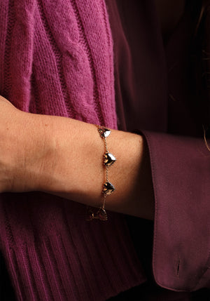 Anabel Aram Heart Station Bracelet featuring a gold chain with small, shiny heart-shaped charms with a beaded border worn on a wrist.