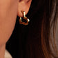 A sculptural 18K gold-plated Small Heart Hoop Earrings piece worn in an earlobe.
