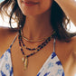 Milos Beaded Necklace by Anabel Aram featuring a gold branch, turquoise and lapis lazuli beaded strands, and a gold fish pendant inlaid with small gemstones.