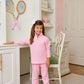 A young girl in Beaufort Bonnet Company Quilted Gates Sweeney Sweatpants stands in a white, neatly organized bedroom with a desk, chair, and tennis rackets on the wall.