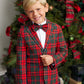 A young boy wearing The Beaufort Bonnet Company’s Baylor Bowtie stands smiling in front of a decorated Christmas tree.