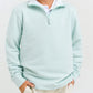 A child smiles with hands in pockets, wearing a light blue Baby Boys' and Boys' Hayword Half-Zip by The Beaufort Bonnet Company and beige pants, standing against a plain background.
