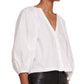 The model is wearing a white Staud Dill Top with puff sleeves.