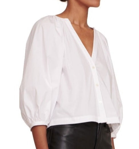 The model is wearing a white Staud Dill Top with puff sleeves.