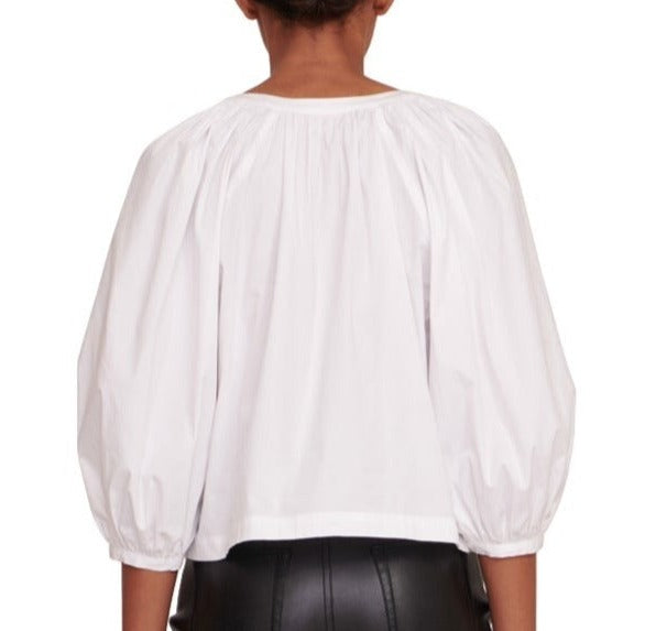 The back view of a woman wearing a Staud Dill Top blouse and leather pants.