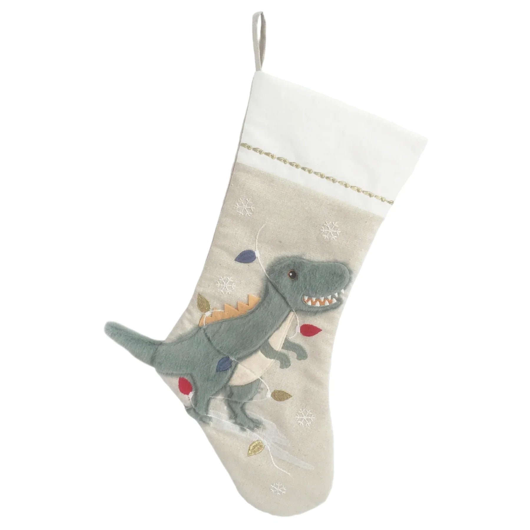 The MON AMI Festive Dino Stocking by Mon Ami features a beige color with a playful green dinosaur adorned with red and white spikes and an eye-catching 3D tail. Scattered decorative elements on a white background make it ideal for personalized monogramming.