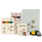 The Konges Slojd Artist Set, ideal for budding artists, features a dinosaur-themed collection with colored pencils, paper, ink pads, and stamps adorned with charming dinosaur and tree illustrations.