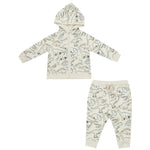 The Angel Dear Artsy Dinos Hoodie and Joggers outfit, crafted from soft organic cotton, features a charming dinosaur print. This beige set includes a hooded zip-up jacket and matching pants, embodying the comfort and playful spirit of Angel Dear.