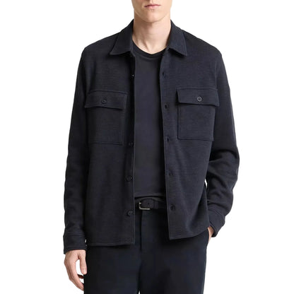 A person wearing Vince's Double Slub Shirt Jacket—an ultra-soft black cotton lyocell layer with two chest pockets—over a black T-shirt and black pants.