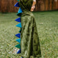 A child wearing the Great Pretenders Dragon Cape with Claws in Green, adorned with blue spikes and made of crushed velvet, stands on the grass in the backyard.