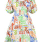 Hunter Bell NYC Drew Dress featuring a vibrant, multi-colored pattern with whimsical designs, including animals and architectural elements, and a smocked elastic waist.