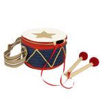 The Meri Meri Drum Bag, featuring a star design, navy blue body, red trim, and beige strap, sits alongside its wooden drumsticks with red felt tips. Perfect for pairing with a Nutcracker costume.