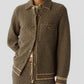 A person wears the Dylan Marquise Shirt by Guest in Residence—a relaxed fit cashmere shirt—layered under a brown and beige patterned button-up jacket with matching pants, both featuring a diamond motif and ribbed trim details for added comfort and style.