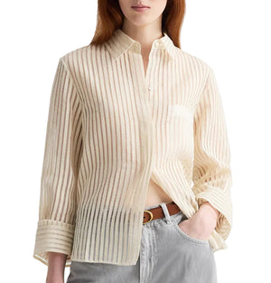 Woman wearing the TWP Boyfriend Silk Top, a cream-colored striped button-down blouse with collar and front pocket, styled with light gray pants and a brown belt.