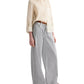 A person wears the Boyfriend Silk Top by TWP in cream, tucked into light gray wide-leg jeans with brown shoes for a relaxed fit.