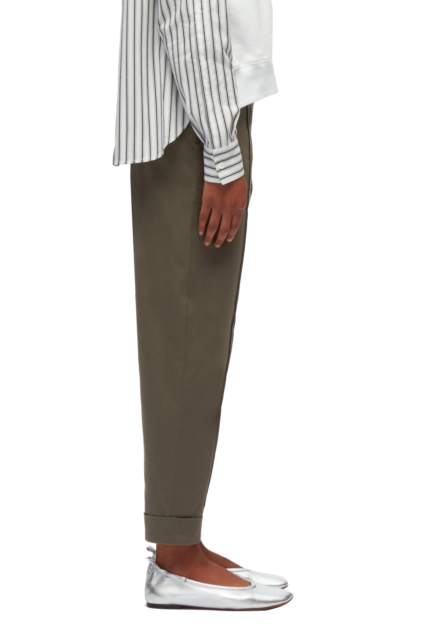 A person wearing a white and black striped shirt, 3.1 Phillip Lim Cropped Carrot Trousers, and silver loafers stands against a white background, with only their right side visible from the shoulder to the shoe.