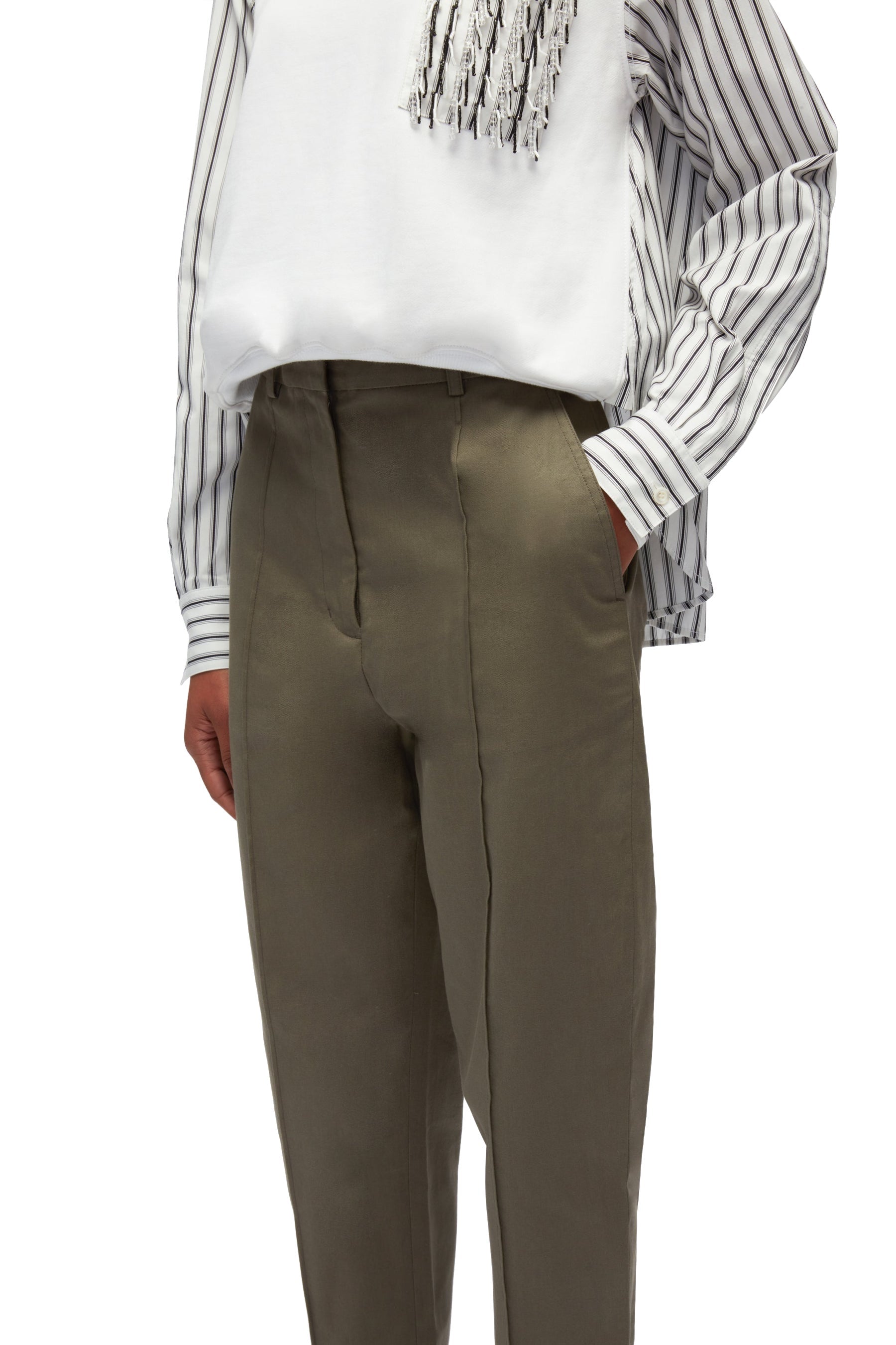 A person wearing 3.1 Phillip Lim olive green slim fit trousers and a white shirt with black striped sleeves and fringe detailing on the chest.