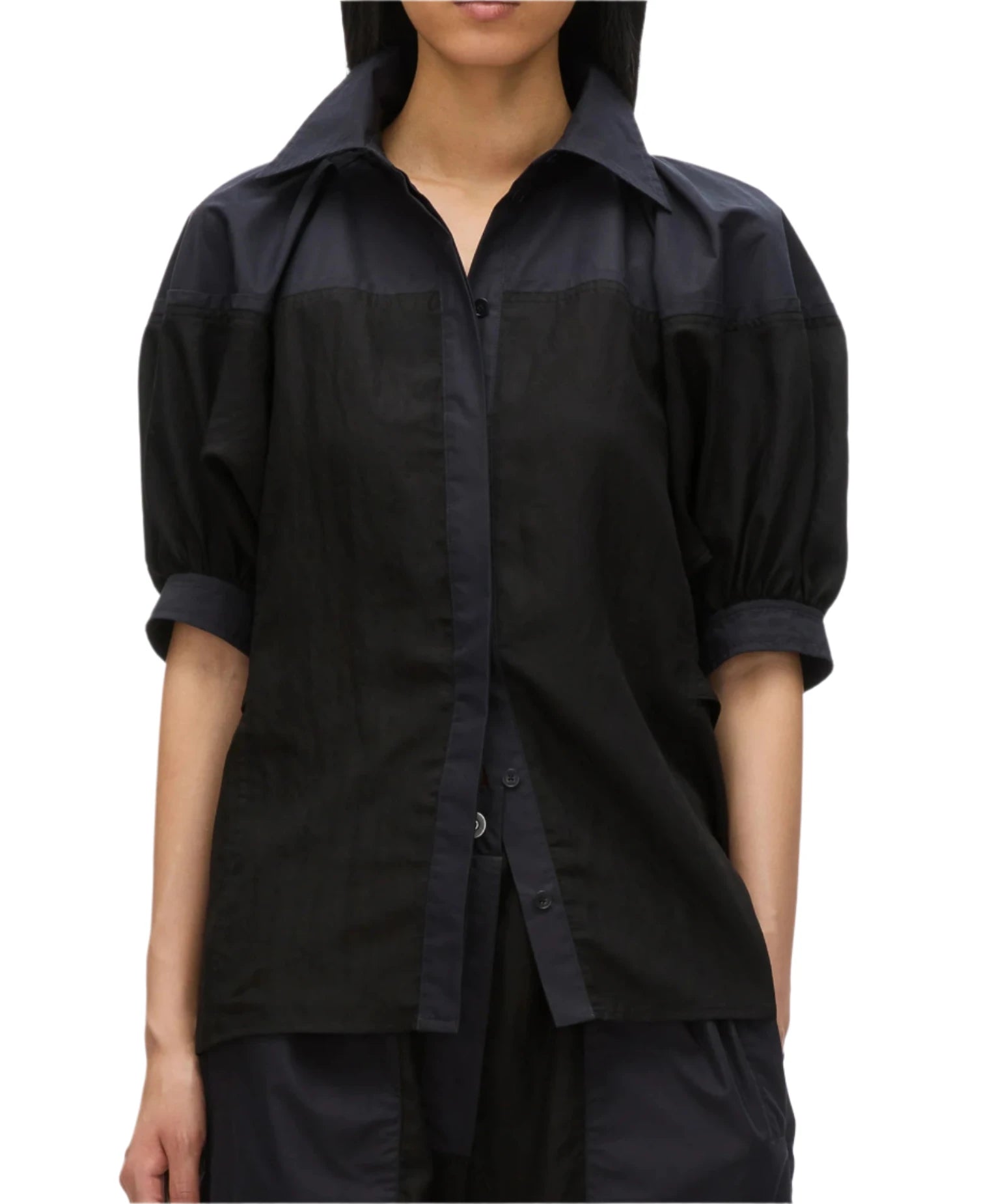 A person wearing the 3.1 Phillip Lim Lantern Sleeve Combo Shirt, a black short-sleeve button-up with a collar, exuding feminine elegance through its structured silhouette.