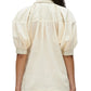 From the back, an individual wears the 3.1 Phillip Lim Lantern Sleeve Combo Shirt, characterized by its light beige hue and loose fit. The shirt's short puffed sleeves radiate a sense of feminine elegance, while its collar and buttoned cuffs gently suggest a structured silhouette.