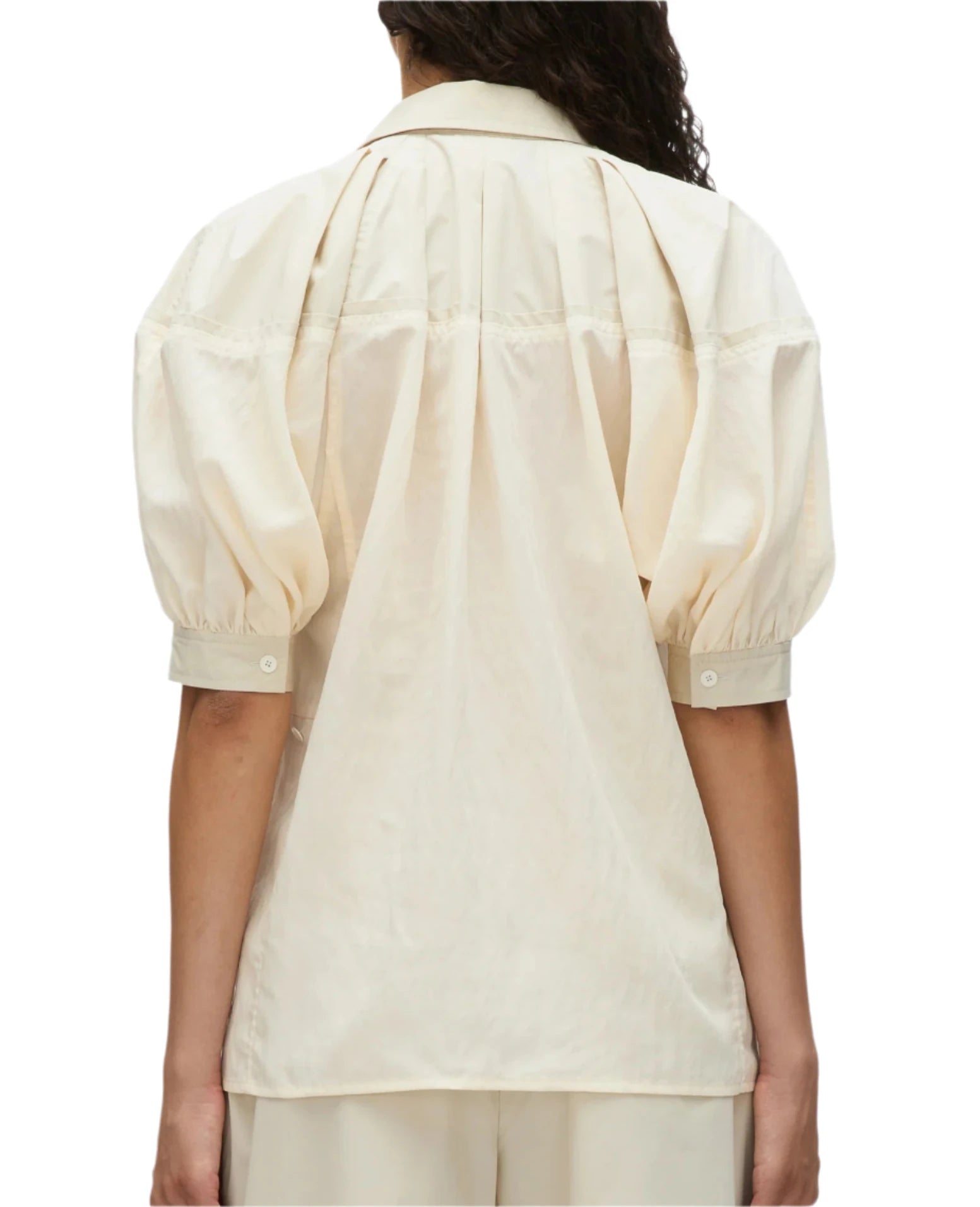 From the back, an individual wears the 3.1 Phillip Lim Lantern Sleeve Combo Shirt, characterized by its light beige hue and loose fit. The shirt's short puffed sleeves radiate a sense of feminine elegance, while its collar and buttoned cuffs gently suggest a structured silhouette.