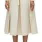 A person wearing a white long-sleeve top and the 3.1 Phillip Lim Utility Pleated Skirt with Belt, paired with beige shoes, stands against a plain background. This versatile piece from 3.1 Phillip Lim is perfect for any occasion.