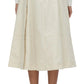 A model displays a white long-sleeve top combined with the 3.1 Phillip Lim Utility Pleated Skirt with Belt, featuring constructed pleats in a beige A-line design, elegantly finished with brown high-heeled shoes. This versatile piece is shown from the back, emphasizing its timeless charm.