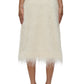 Back view of a person in elegant eveningwear: a 3.1 Phillip Lim Fringe Slip Skirt in cream paired with black heeled sandals against a plain background.