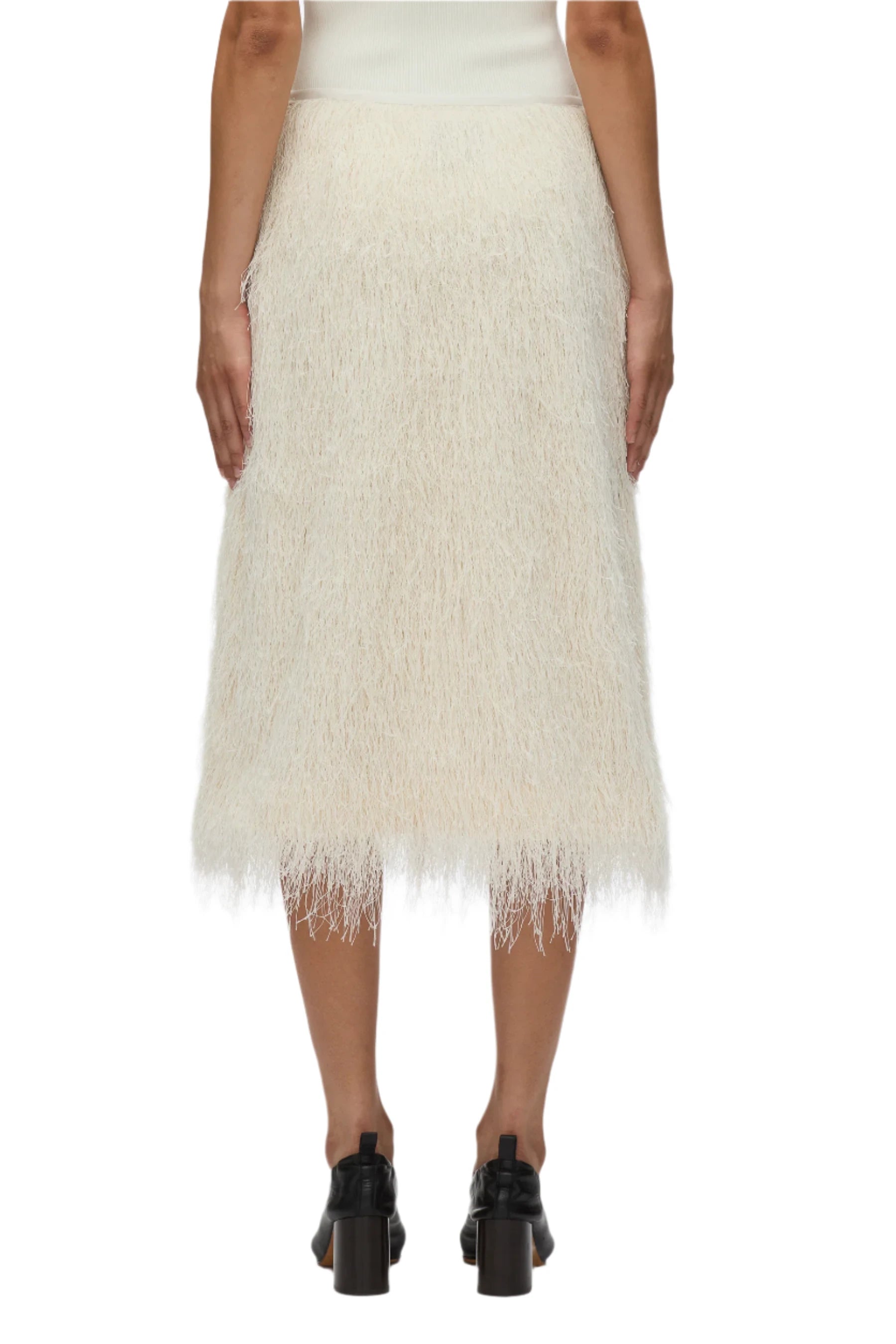 Back view of a person in elegant eveningwear: a 3.1 Phillip Lim Fringe Slip Skirt in cream paired with black heeled sandals against a plain background.